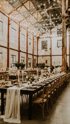 a long table set up with white linens and candles for an elegant wedding reception