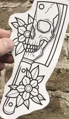 a hand holding up a sticker with a skull and flower design on the side