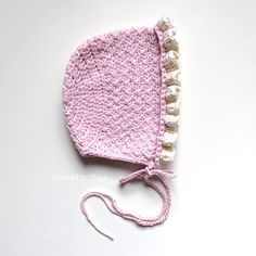 a pink crocheted hat with white trim