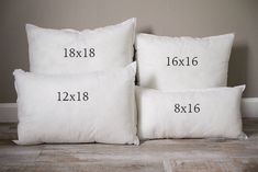 three white pillows with numbers on them sitting next to each other in front of a wall