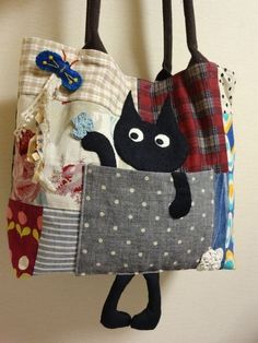 a black cat in a patchwork bag hanging from a hook