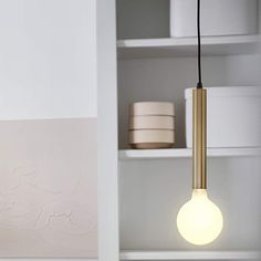 a light that is hanging from the ceiling in a room with white walls and shelves