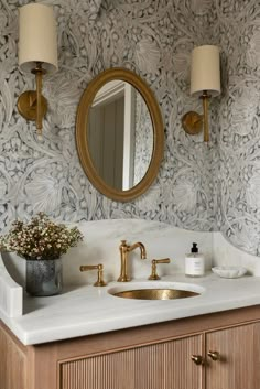 a bathroom with a sink, mirror and gold faucet on the counter top