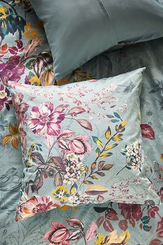 the comforter is made up with many colorful flowers and leaves on it, along with two pillows