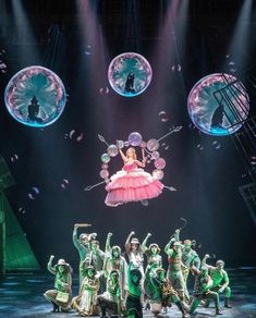 a group of people standing on top of a stage with bubbles in the air above them