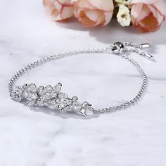 Surround her with flowers all year long. Buy that special someone this silver flower bracelet, whether she is celebrating a holiday or if she is just a lover of flowers. Crafted in sterling silver, the bracelet consists from cluster flowers at the center on a classic cross chain, which shows elegance and sparkle. The bolo bracelet is easy to adjust the size to fit for her wrist to create different looks. Surprised her with this charming piece.Carat Weight: 1.74 ctStone Size: 1.3,1.5,1.7,2,2.5,3 Elegant Sterling Silver Bracelets With Flower Charm, Elegant Silver Flower Bracelets, Anniversary Bracelets With Flower Charm, Flower Shaped Anniversary Bracelets, Elegant Sterling Silver Flower Bracelets, Elegant Sterling Silver Flower Bracelet, Sterling Silver Flower Bracelets For Wedding, Elegant Silver Bracelets With Flower Shape, Elegant Silver Bracelets In Flower Shape