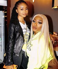 two women standing next to each other in front of a refrigerator