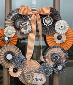 a wreath made out of paper fans on a front door with a ribbon tied around it