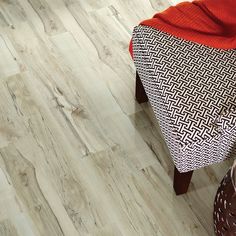 a close up of a wooden floor with a chair next to it and an orange blanket