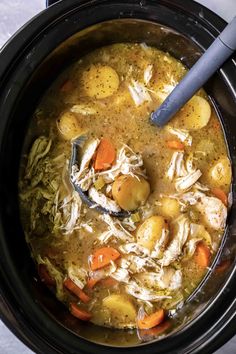 a crock pot filled with chicken, potatoes and carrots next to a spoon