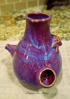 a purple vase sitting on top of a table next to a white cloth covered counter