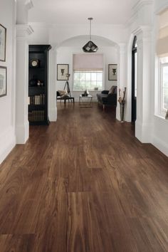 a living room with hard wood floors and white walls, along with pictures on the wall