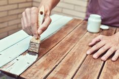 a person painting the outside of a wooden table