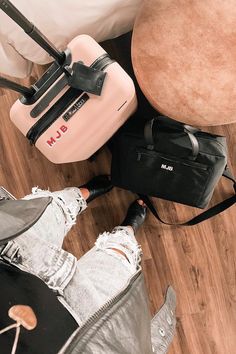 two pieces of luggage sitting on the floor next to a person's legs and foot