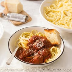 two bowls of spaghetti and meat with bread on the side