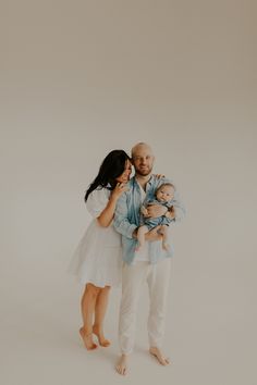 a man and woman holding a baby in their arms while standing next to each other