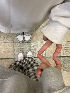 two people standing next to each other in front of a tile floor with their hands on the ground