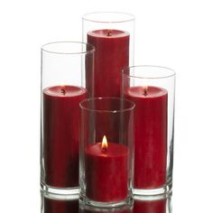 three red candles in glass vases with one lit and the other turned upside down