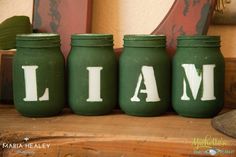 three green jars with white letters that spell out the word i am on them sitting on a wooden shelf