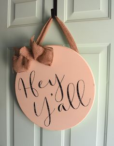 a wooden sign that says hey y'all hanging on a door with a bow