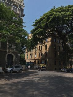 an empty street with cars parked on the side and people walking down the road in front