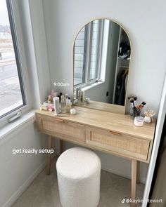 a vanity table with a mirror, stool and other items on it in front of a window