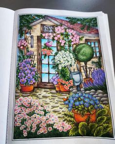 an open book with flowers and potted plants on the pages, in front of a house