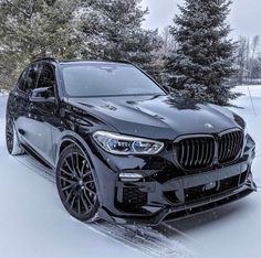 a black bmw suv parked in the snow