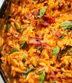 a pan filled with pasta and bacon on top of a table