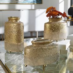 three vases sitting on top of a glass table