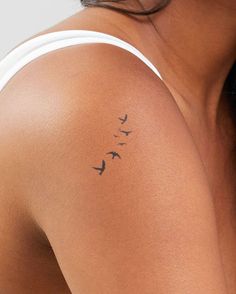 a woman's arm with a bird tattoo on the left side of her shoulder