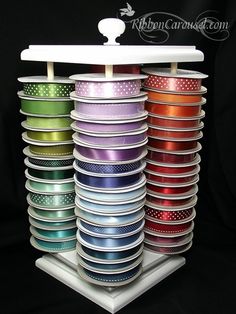 many different colored ribbons are stacked on top of each other in a display case with a white stand