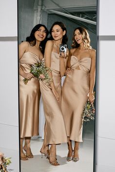 three bridesmaids are standing in front of a mirror and taking a selfie