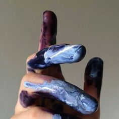 someone is holding their fingers painted with purple and blue paint that looks like they are pointing to the sky