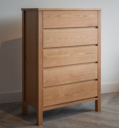 a wooden dresser sitting on top of a hard wood floor next to a white wall