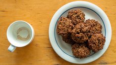 a white bowl filled with cookies next to a cup of coffee on top of a wooden table