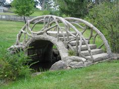 a wooden bridge made out of branches in the grass