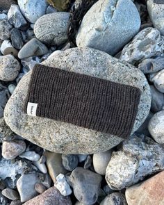 a knitted headband sitting on top of some rocks and gravel next to water