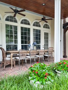 an outdoor dining area with chairs, tables and ceiling fans in front of a house