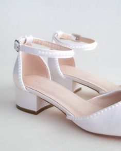 a pair of women's white shoes with pearls on the heel and ankle straps