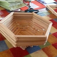 a wooden basket sitting on top of a colorful floor next to scissors and other crafting supplies