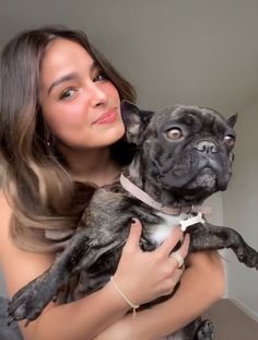 a woman is holding a small dog in her arms and looking up at the camera