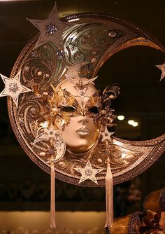 a gold mask with stars and moon decorations on it's face, in front of a mirror