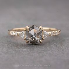 an engagement ring with three diamonds on the side and one diamond in the middle, sitting on a gray surface