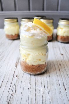 small mason jars filled with dessert and topped with whipped cream, lemon wedges, and graham crackers