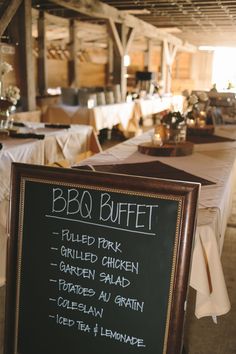 a blackboard sign sitting on top of a table next to tables covered in white linens