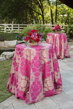 two tables with pink tablecloths and flowers on them