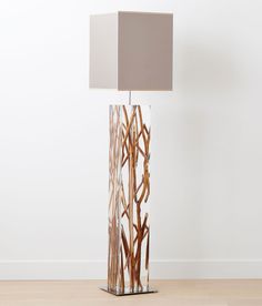 a lamp that is on top of a wooden floor next to a wall with a square light shade