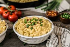 two white bowls filled with macaroni and cheese on top of a wooden table