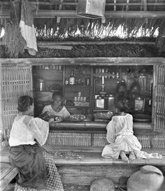 two women sitting at a counter in front of a store